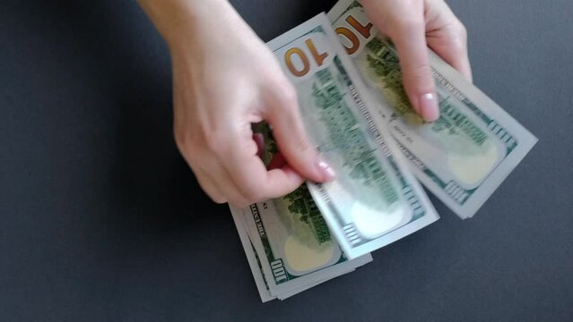 Women's hands are counting American dollars. 4K footage