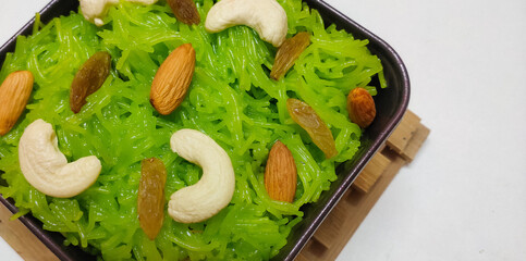 Closeup of Indian traditional sweet vermicelli or semiya kesari placed in a isolated White background with selective focus and copy space for inscription. Topped with dry fruits and nuts. 