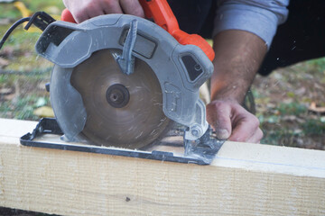 Close-up of a carpenter using a circular saw to cut a large board of wood 