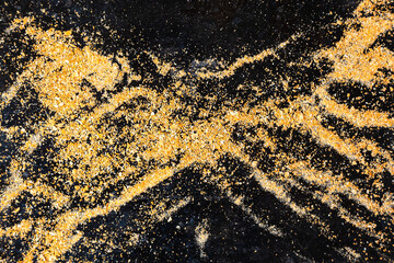 Small bread crumb on black. Gold dust on a black background. Small particles of gold rock on black.