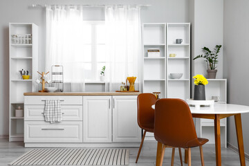 Interior of light kitchen with dining table and shelving unit