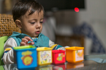 Young baby boy playing with his colorful toys on a glass table