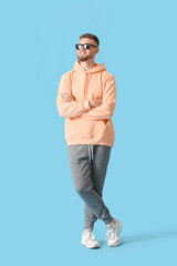 Young guy in stylish hoodie on color background