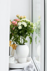 Tray with cup of coffee and roses in vase on windowsill