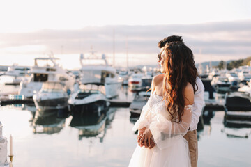 Happy lovers, the bride and groom in elegant wedding dresses go on a honeymoon by sea on  yacht in...
