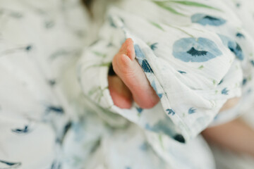 Newborn baby feet sticking out of muslin blanket with blue poppies