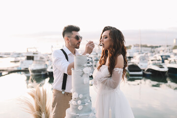 Happy lovers, the bride and groom in elegant wedding dresses go on a honeymoon by sea on  yacht in...