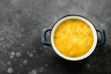 Healthy split pea soup puree in pot on dark background. Top view, flat lay, copy space.