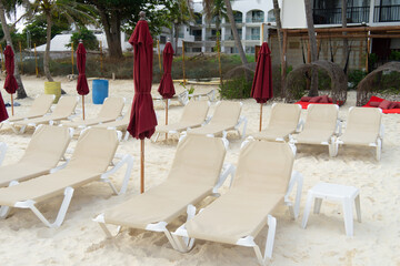 Empty sunbeds on the sandy beach. Folded umbrellas, hotel beach without tourists. Consequences of the covid-19 pandemic.