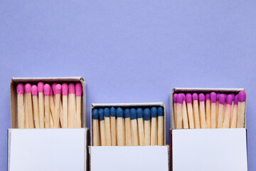 Boxes with different new matchsticks on purple background, closeup