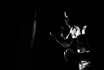 Young man hits a punching bag over black background. Black and white high contrast image. © Gustav Patterson