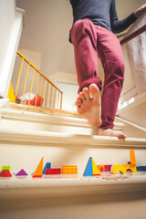Dad walking down staircase filled with children toys - obrazy, fototapety, plakaty