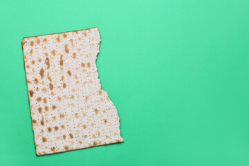 Piece of Jewish flatbread matza for Passover on green background