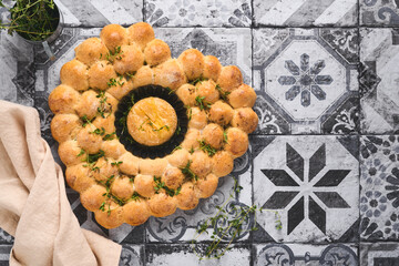 Roasted camembert cheese and homemade bread heart shaped and thyme on rustic background. French cheese. Concept of romantic love for Valentines Day. Top view, copy space.