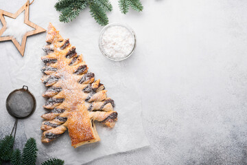 Puff pastry Christmas tree with chocolate paste, sprinkled with powdered sugar on a gray background. Christmas or Xmas pastries. Top view. Copy Space