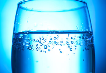 Glass of clear water on blue background, closeup
