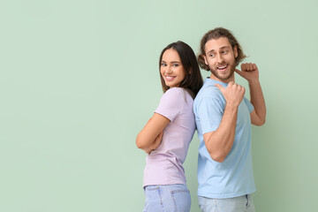 Young couple in stylish t-shirts on green background