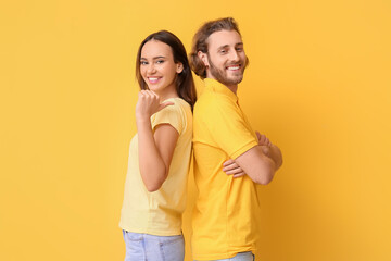 Young couple in stylish t-shirts on yellow background