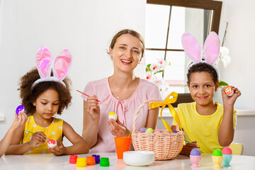 Family paints eggs for Easter holiday sitting at the table