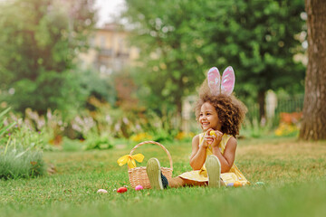 Little Black girl wtfring bunny ears gathering Easter eggs