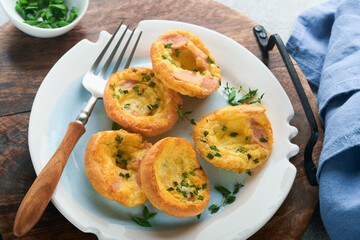 Egg muffins with green onions, bacon, cheese and tomatoes on white plate on light background. Healthy high protein and low carb breakfast, ready to eat.