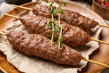 Plate of skewers with tasty lula kebab on table, closeup