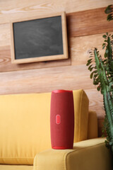 Wireless portable speaker on armchair near wooden wall