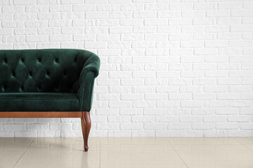 Stylish sofa near white brick wall