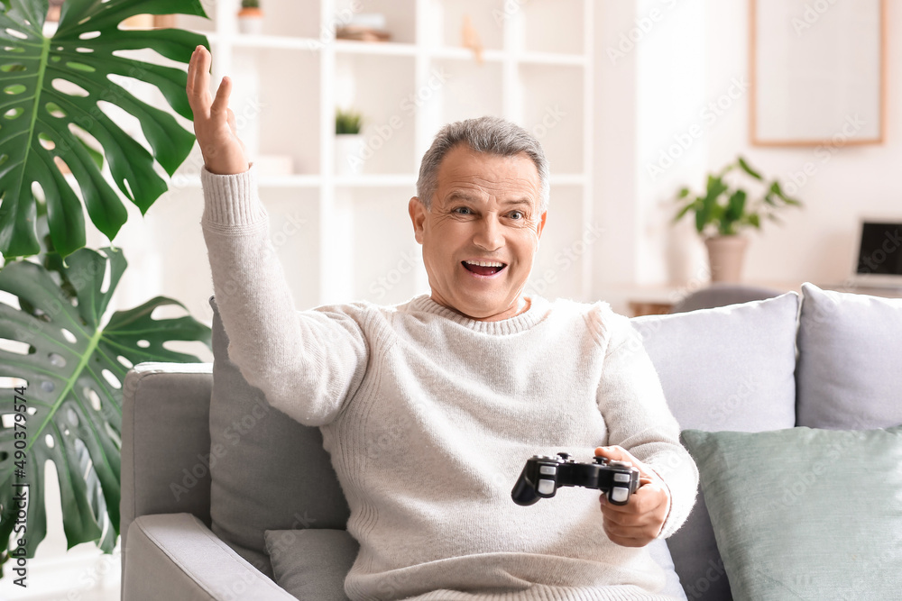 Wall mural happy senior man playing video game at home