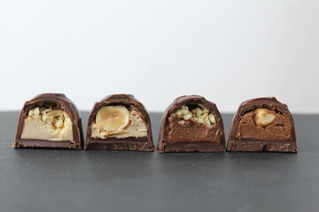 chocolate corus candies in section with a white chocolate filling with hazelnuts peanuts praline ganache on a gray background with space for text and copyspace. Day chocolate sweets without diet