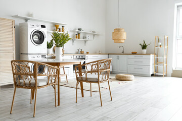 Interior of light kitchen with washing machines, white counters and shelves