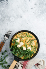 Omelet with spinach, green beans, potato and spinach healthy food in black frying pan on grey stone old rustic background. Traditional frittata for breakfast Eggs tortilla Top view flat lay Copy space