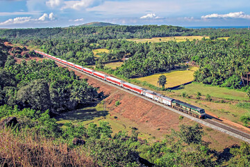  Colorful Rajdhani express train through fields with nice sky in Honnavar, Karnataka,India.