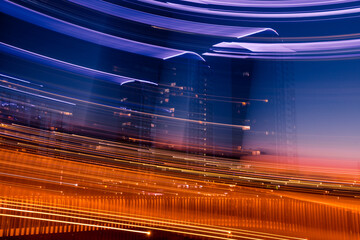 Night city street abstract background. Urban illumination of modern buildings with motion blur effect. Futuristic effect of light trails from camera motion.