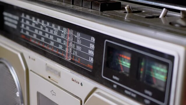 Tuning the Frequency, Searching Wave on an Old Vintage Analog Radio. Search for a music radio station on a dial scale on panel of a short-wave portable FM receiver, player, tape recorder 80s, 90s.