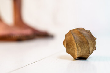 Round wooden massager on a white background. Ribbed massager for muscle relaxation. Practicing standing on nails in the background