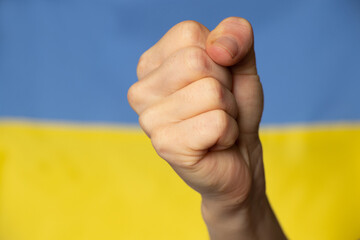 A female fist on the background of the national flag of Ukraine, the strength and anger of a...
