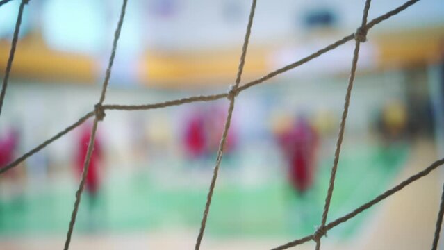 Sports mesh on blurred background of volleyball players. Teamwork and competition concept, selective focus.