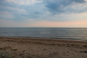 Beautiful view of sandy beach at sunset of in Mediterranean Sea against  backdrop of thunderclouds. Greece.