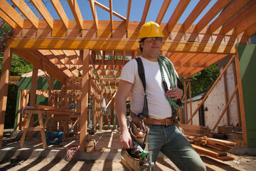 Portrait of a construction worker wearing a hard hat and a tool belt while standing on the construction site