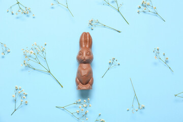 Chocolate Easter bunny and gypsophila flowers on color background