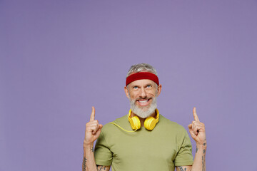 Promoter fancy elderly gray-haired bearded man 40s years old in headband khaki t-shirt point up on workspace area copy space mock up isolated on plain pastel light purple background studio portrait.