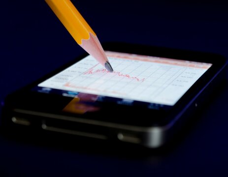 Pencil on illuminated Smartphone with Financial Chart in Switzerland.