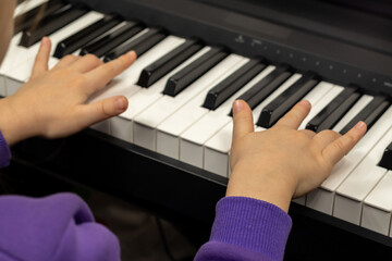 Selective focus on children's fingers and piano keys for playing the piano. Musical instrument for concert or music teaching.