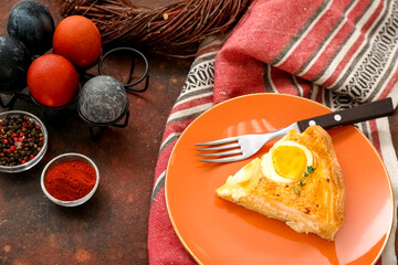 Plate with piece of tasty Easter tart, painted eggs and spices on grunge background