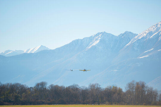 Airplane and a Glider with Snow-capped Mountain in Locarno, Switzerland.