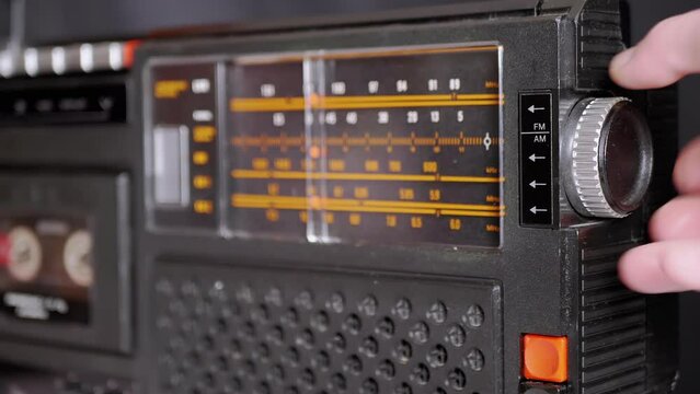 Female Fingers Adjusting the Frequency on an Old Vintage Analog Receiver. Search for a music radio station on a dial scale on panel of a short-wave portable FM radio, player, tape recorder 80s, 90s.