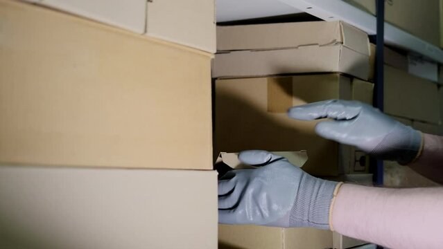 A man in gloves steals goods from a box in a warehouse. Problems with theft and security in the office
