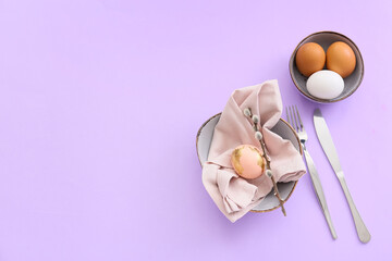 Beautiful table setting with Easter eggs and willow branch on lilac background