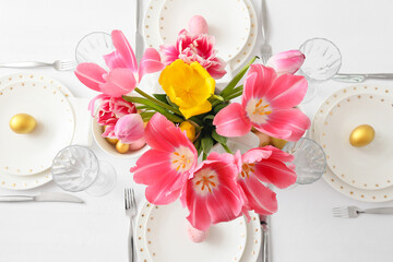 Vase with tulips and Easter table setting in room, closeup